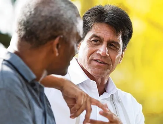Image of two men talking with one another