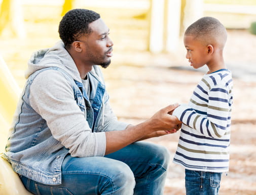 A supportive moment between a parent and an elementary school aged child in a park