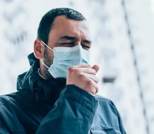 Man wearing a face mask and coughing.