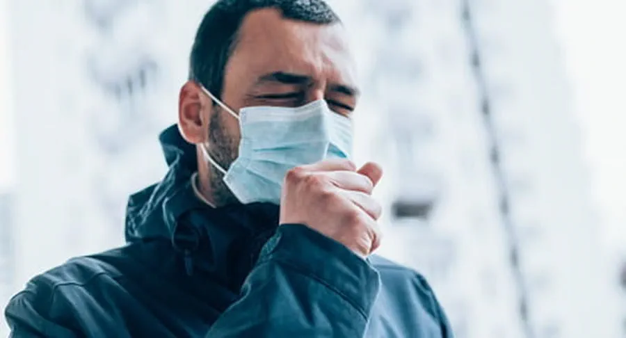 Man wearing a face mask and coughing.