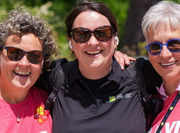 Trois participants du Relais pour la vie sourient et portent des t-shirts de l’événement de la Société canadienne du cancer.