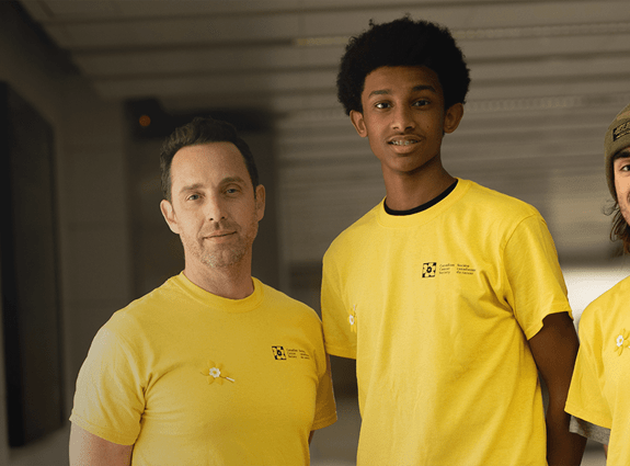 Three people standing and looking at the camera wearing yellow Canadian Cancer Society T-shirts.
