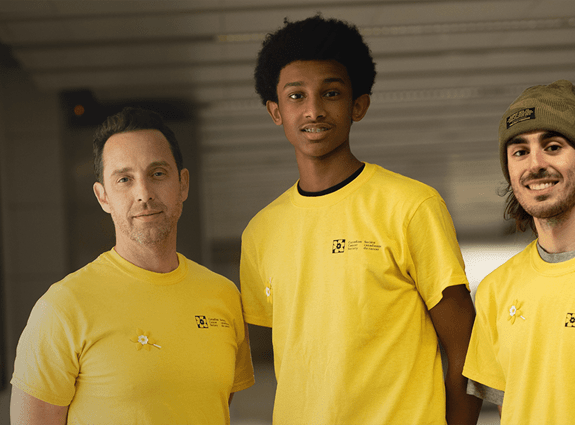 Three people standing and looking at the camera wearing yellow Canadian Cancer Society T-shirts.