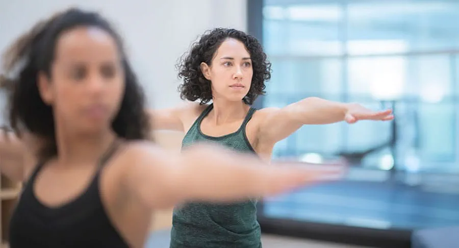 Two people exercising and posing with their arms extended at their shoulders.