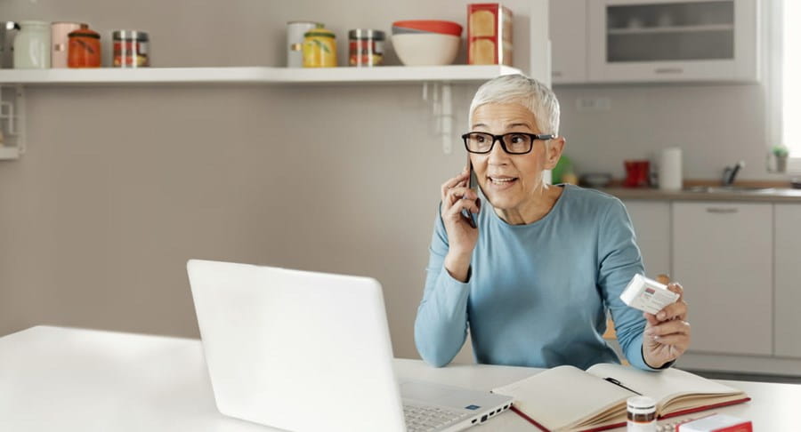 Une femme au téléphone, tenant des médicaments.