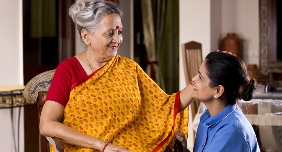 A woman and elderly woman smile while embracing one another