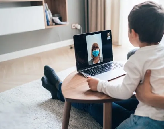 Woman leans her head on man’s shoulder as they look at a laptop screen.