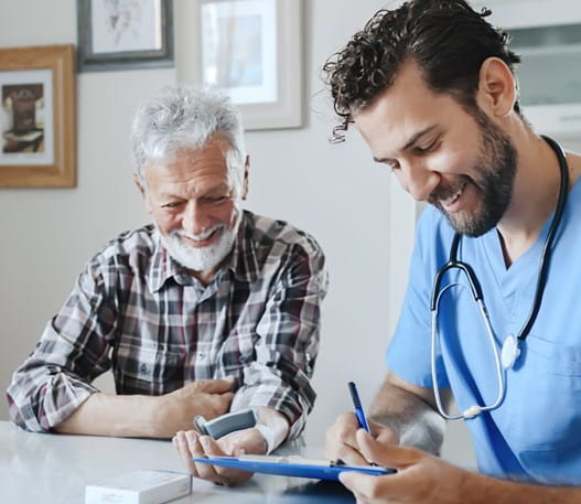 A doctor and his patient are smiling together while the doctor takes notes