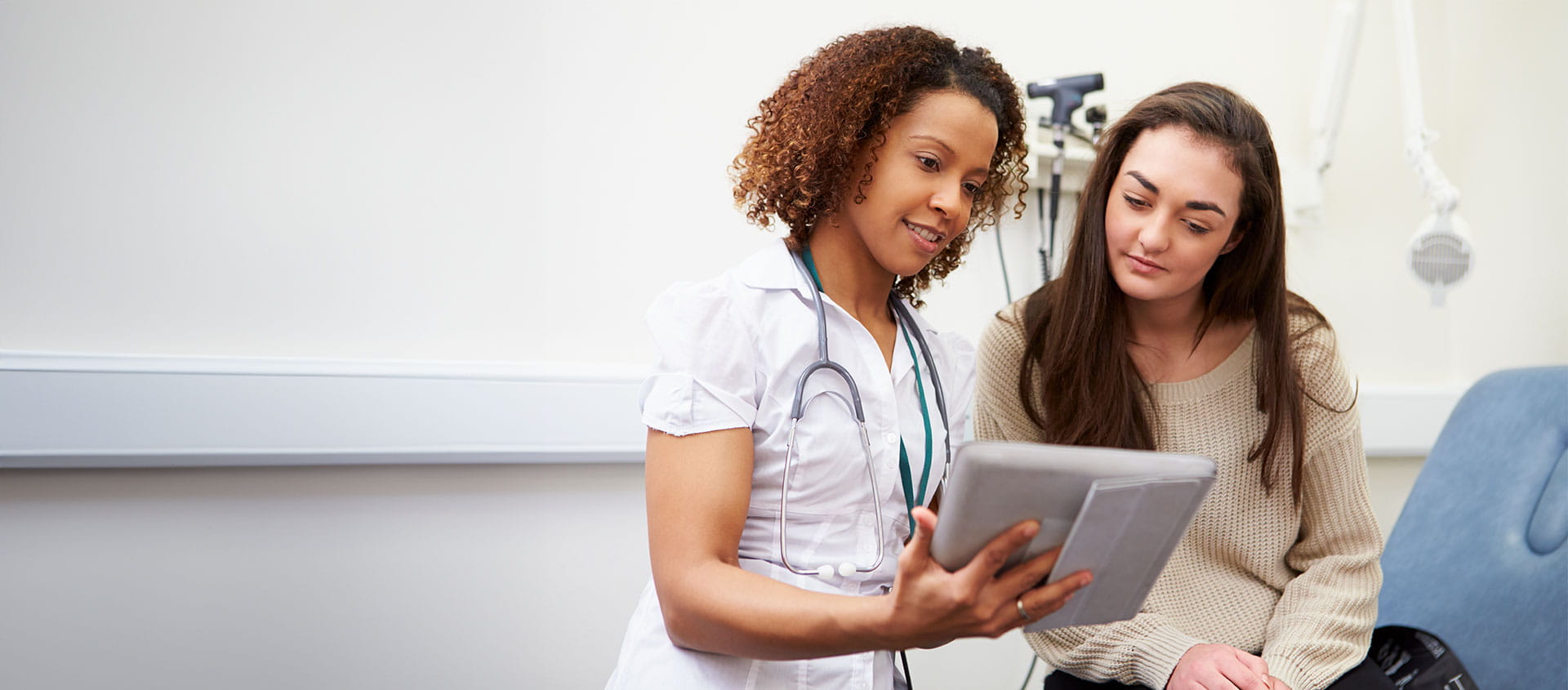 Une patiente et une professionnelle de la santé en train de regarder quelque chose sur une tablette