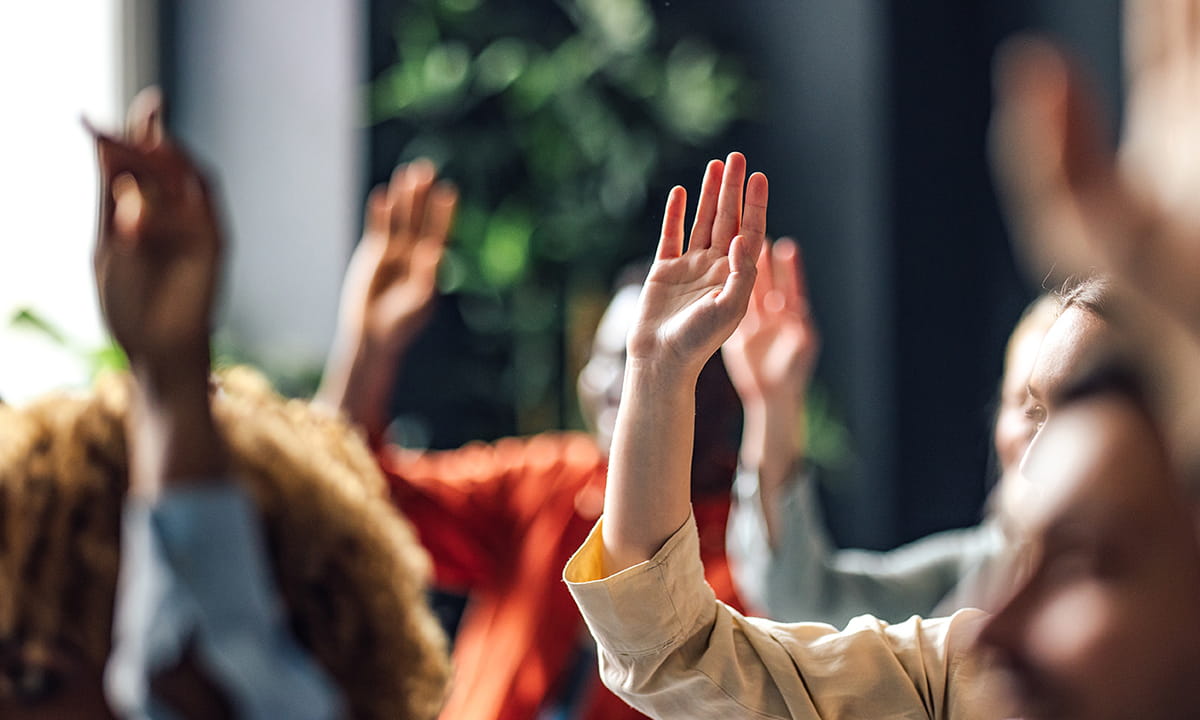 People raising their hands during a group meeting or discussion