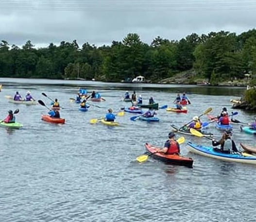 A large group of people canoeing together on a lake.