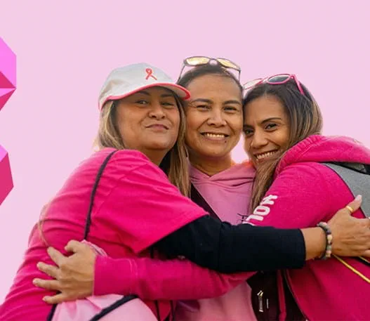 Three women leaning against one another and smiling.