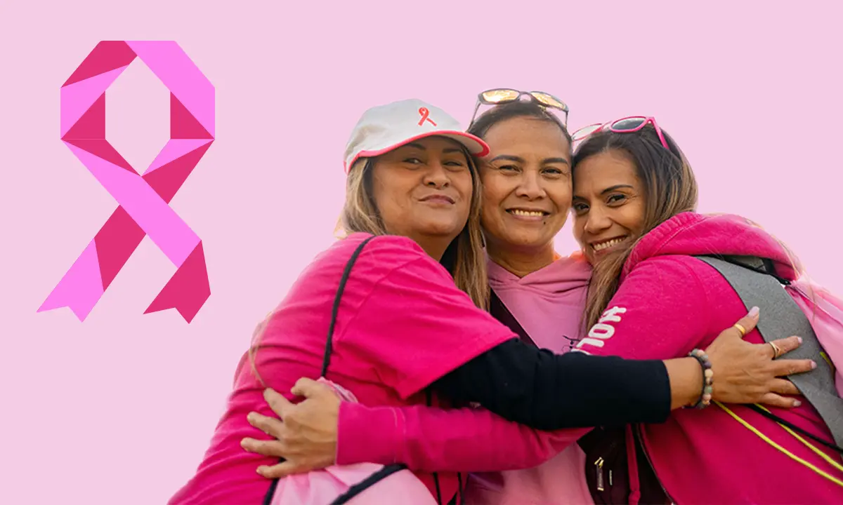 Three women leaning against one another and smiling.