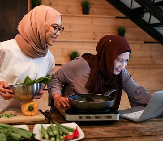 Two people cooking meal with online instructions