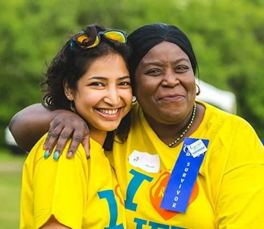 A woman wearing a survivor badge posing with another girl in a Relay For Life t-shirt.