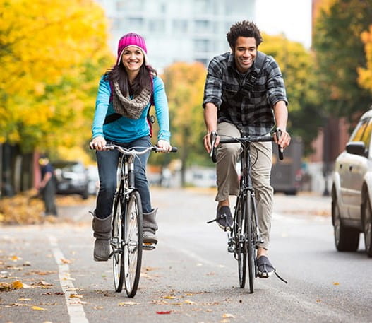 a man and woman cycling down the street in autumn 