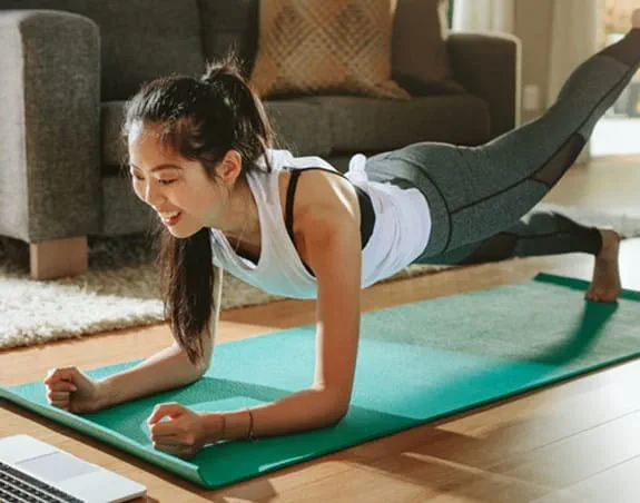 A person doing yoga in front of a laptop.