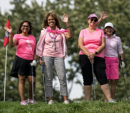 Group of women in pink waving on golf course