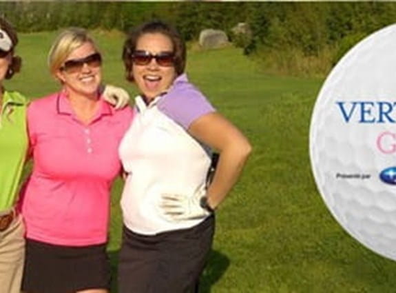 Trois femmes souriantes et debout sur un terrain de golf