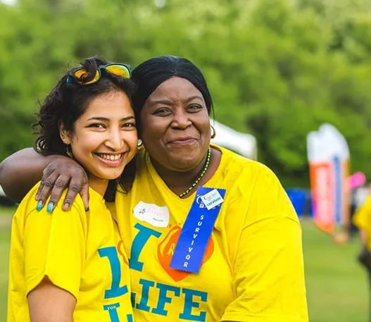 A young woman and older woman wearing relay for life t-shirts smile at the camera