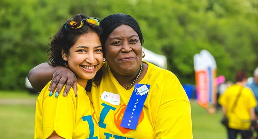 A young woman and older woman wearing relay for life t-shirts smile at the camera