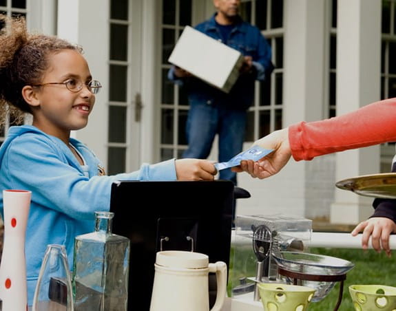 Young child accepts money at yard sale.