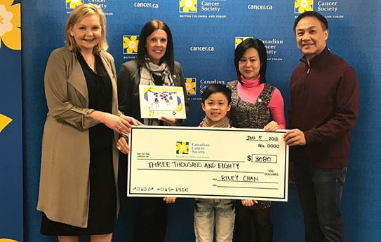 Four adults and one child standing in front of a blue backdrop and holding a cheque for three thousand and eighty dollars. 