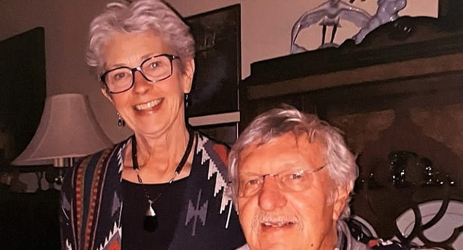 Un couple marié souriant en tenue décontractée, lunettes au visage.