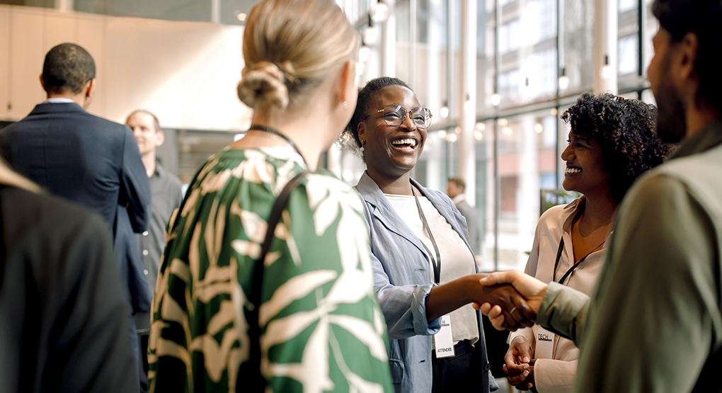 Professionals meeting and shaking hands in a bright, modern office setting.