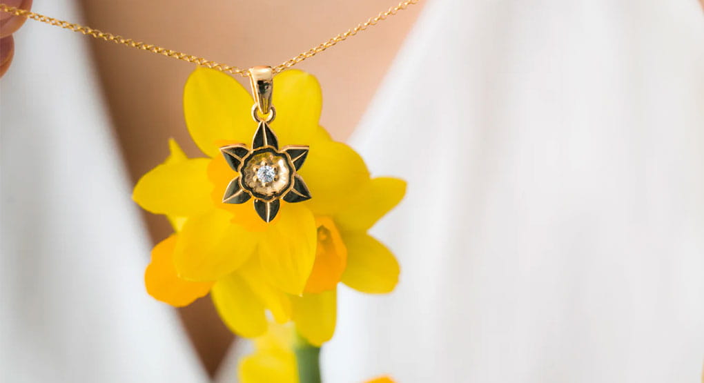 A close up shot of a daffodil pendant necklace.