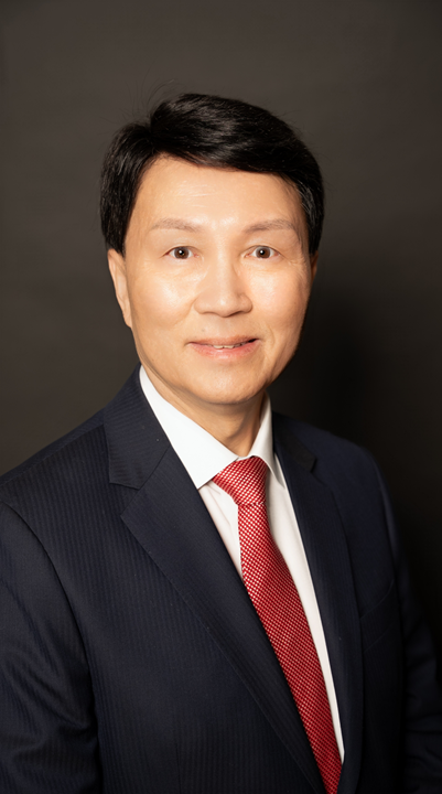 Bammy wong Bammy Wong smiling. He wears a dark coloured suit, white shirt and red tie.