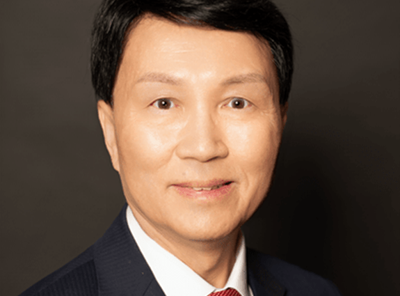 Bammy wong Bammy Wong smiling. He wears a dark coloured suit, white shirt and red tie.