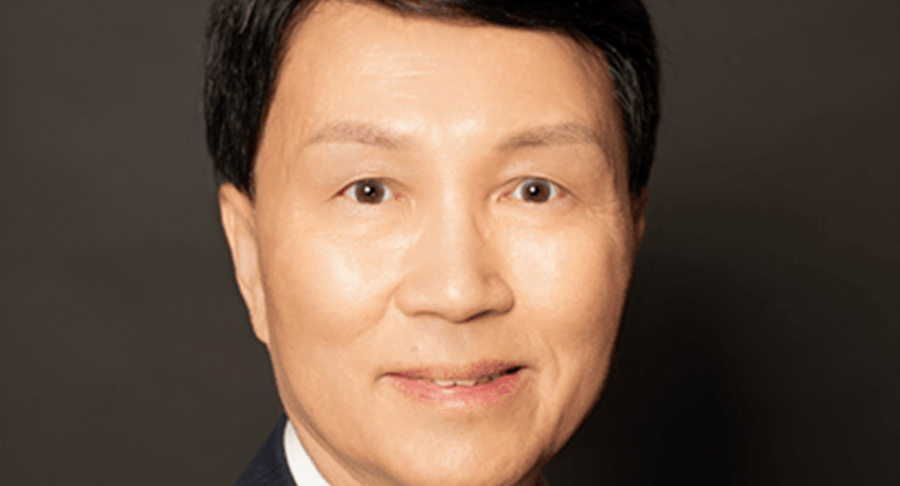 Bammy Wong Bammy Wong souriant. Il porte un complet de couleur foncée, une chemise blanche et une cravate rouge.