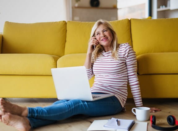 Une femme assise par terre avec son ordinateur portable