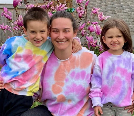 Alexis and her two children in their backyard, wearing tie dye shirts and smiling.