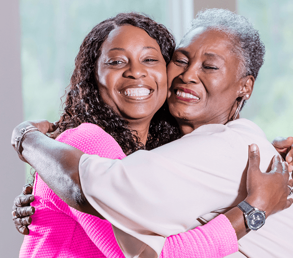 Two happy women hug each other smiling
