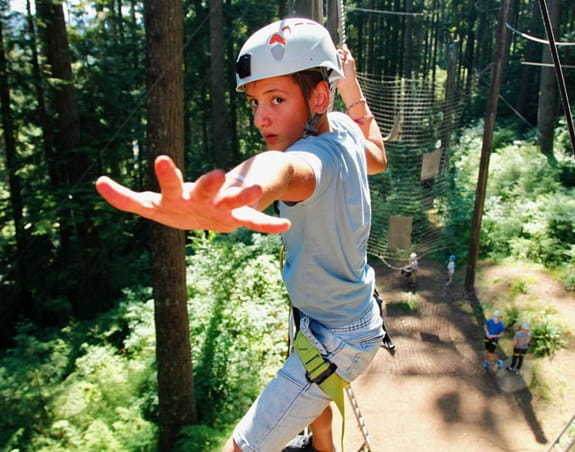 Teenage boy, reaching on a rope ladder.