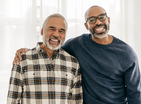 Son stands with arm around his father, smiling  