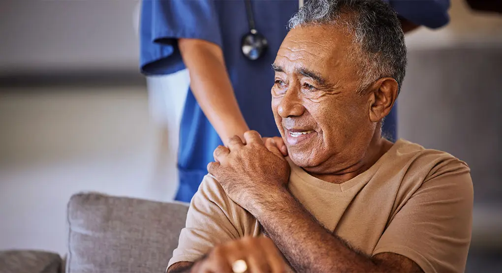 Un soignant tenant la main d'une personne triste et faisant preuve de gentillesse.