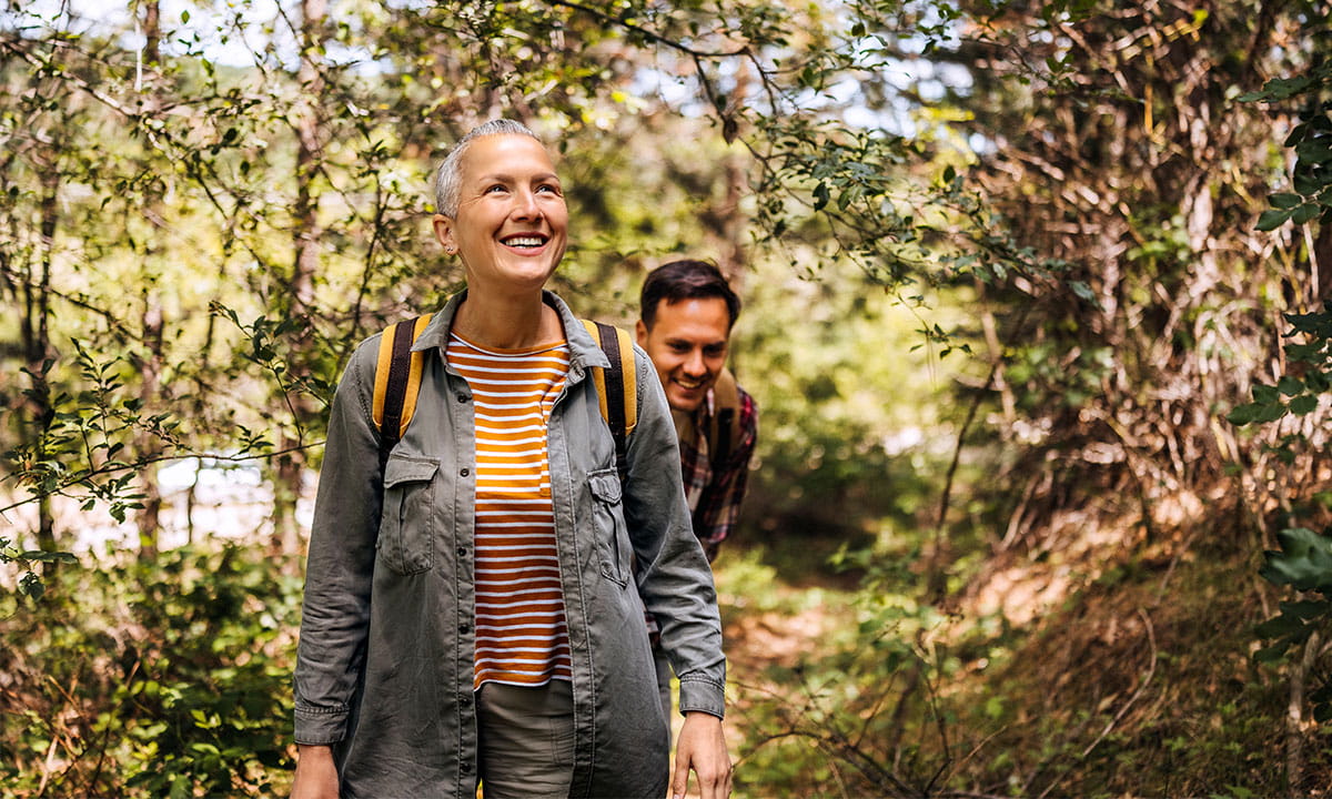 A woman and man walking in the forest and smiling 