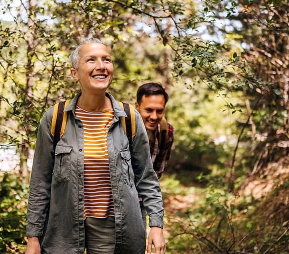 A woman and man walking in the forest and smiling