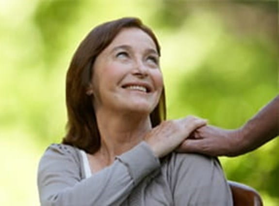 Femme regardant une personne derrière elle ayant placé une main sur son épaule.