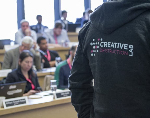 A man in front of an audience wearing a sweatshirt that says Creative Destruction Lab on the back.