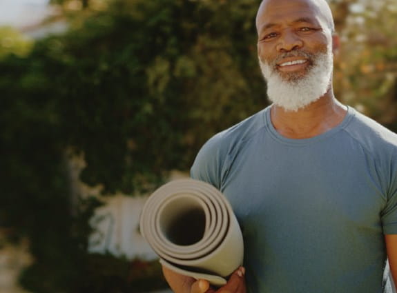 Man holding a yoga matt outdoors