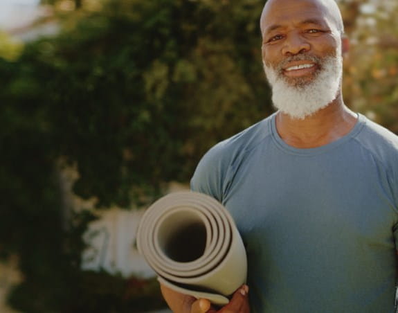 Man holding a yoga matt outdoors