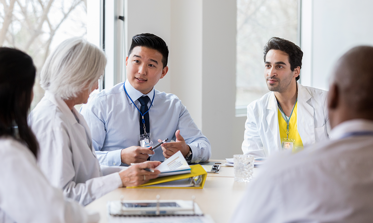 Des professionnels de la santé réunis à une table, examinant des documents et discutant des soins.