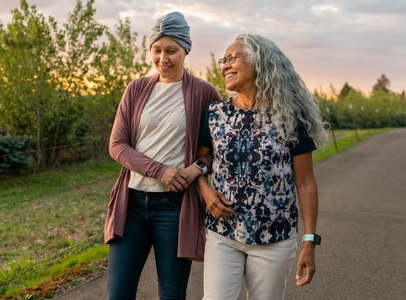 Two women walking together arm-in-arm and smiling