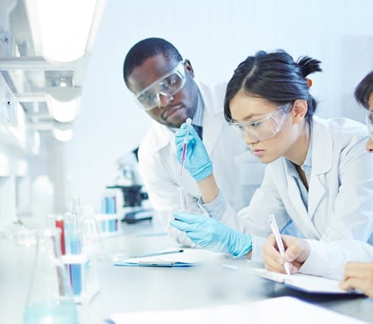 A female researcher in a lab, working with 2 other male researchers.