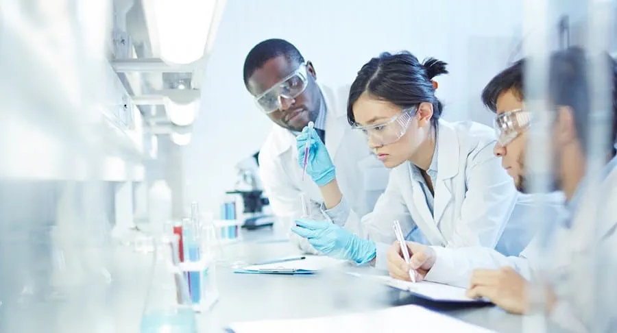 A female researcher in a lab, working with 2 other male researchers.