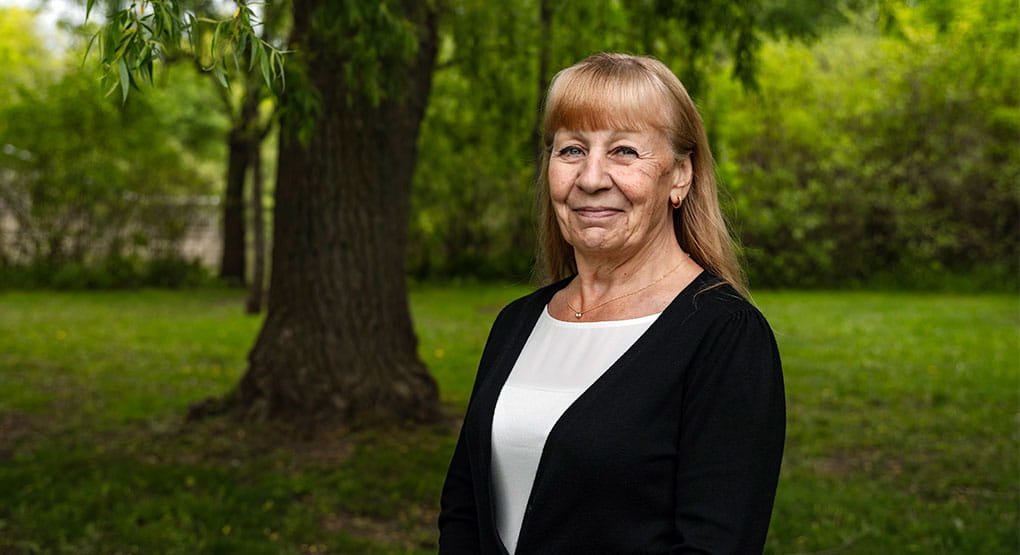 Gayle Archibald standing in front of a tree, smiling at the camera.